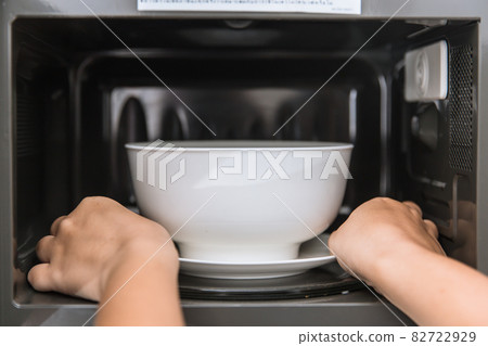 People putting food ceramic bowl in to the Microwave for reheating food. 82722929