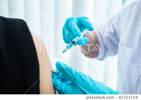 Doctor making a vaccination into patient with needle getting immune vaccine at arm for flu shot, coronavirus protective of epidemic Doctor making a vaccination into patient with needle getting immune vaccine at arm for flu shot, coronavirus protective of epidemic 82723154