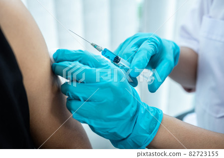 Doctor making a vaccination into patient with needle getting immune vaccine at arm for flu shot, coronavirus protective of epidemic Doctor making a vaccination into patient with needle getting immune vaccine at arm for flu shot, coronavirus protective of epidemic 82723155
