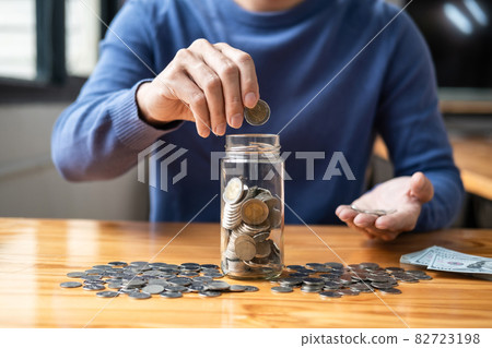 Young man putting coins into bottle planning growing saving to strategy with money box for future plan fund of travel, education, home and retirement 82723198