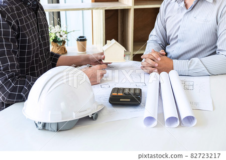 Team of architects or engineering consulting and analyzing working on objects tools and construction drawings inspection, discussing planning new architectural project on blueprint and model house 82723217