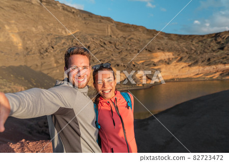 Travel summer Spain destination selfie of interracial couple tourists selfie photo on hike Asian woman, caucasian man hikers happy. Lanzarote National Park, Spain, Europe 82723472