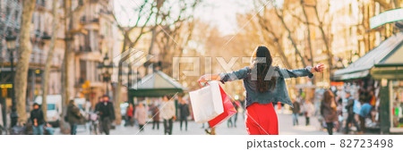 Shopping fun happy woman with bags spending buying new clothes in stores of Barcelona, Spain. Panoramic banner of happy girl with open arms in freedom Shopping fun happy woman with bags spending buying new clothes in stores of Barcelona, Spain. Panoramic banner of happy girl with open arms in freedom 82723498