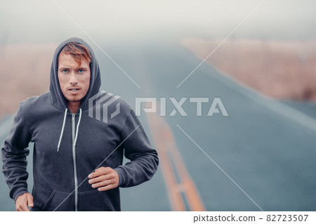 Morning run endurance runner athlete running outside in cold winter training cardio. Man breathing while jogging outdoors in hoody Morning run endurance runner athlete running outside in cold winter training cardio. Man breathing while jogging outdoors in hoody 82723507