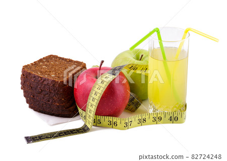 Rye bread apples and juice in glass on a white background with a measuring tape 82724248