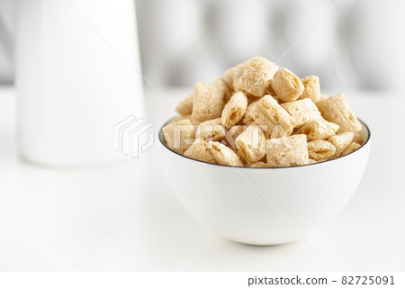 Dry breakfast cereal pads with milk on a light table. selective focus Dry breakfast cereal pads with milk on a light table. selective focus 82725091