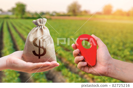 Hands with location pin and money bag. Buying and selling land. Land market. Estimation cost of plots. Legal regulation of property. Agriculture agribusiness. Transport and construction industry. 82725216