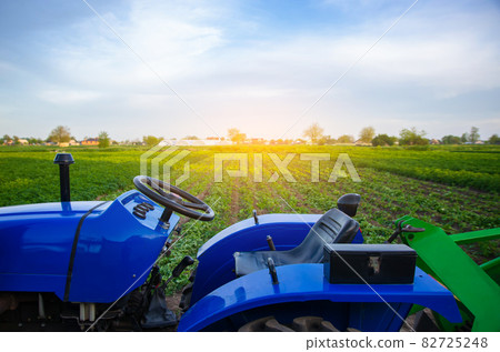 Blue tractor on farm field. Agricultural machinery and technology. Farming and vegetable growing. Modernization. Subsidies and tax refunds for purchase of new equipment. Agriculture and agro industry 82725248