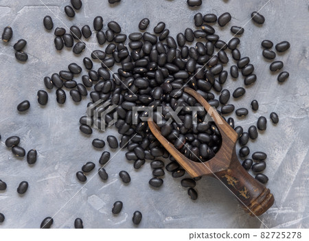 Wooden scoop with dry black beans on grey table 82725278