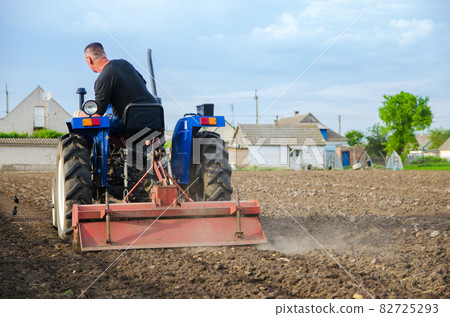 A farmer on a tractor cleans the field after harvest. Running a small agribusiness. Farm work. Softening soil before planting crops. Farming. Loosening, land cultivation. Mechanization in agriculture. A farmer on a tractor cleans the field after harvest. Running a small agribusiness. Farm work. Softening soil before planting crops. Farming. Loosening, land cultivation. Mechanization in agriculture. 82725293