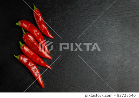 Five chilli peppers on black slate board. Flat lay. Copy space. Five chilli peppers on black slate board. Flat lay. Copy space. 82725540