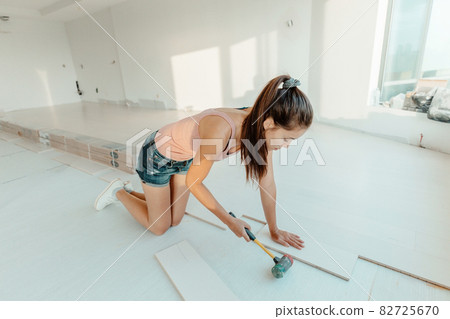 Engineered hardwood new floor installation in house remodeling woman installing wood flooring herself DIY project Engineered hardwood new floor installation in house remodeling woman installing wood flooring herself DIY project 82725670