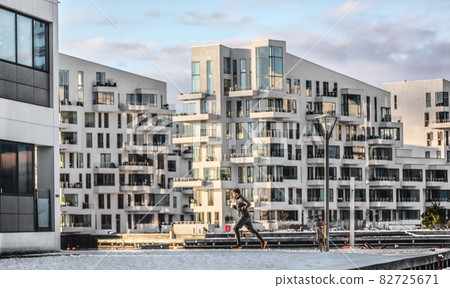 City run winter running man jogging through Copenhagen apartment buildings training cardio on city street. Active healthy lifestyle man runner outdoors in cold weather City run winter running man jogging through Copenhagen apartment buildings training cardio on city street. Active healthy lifestyle man runner outdoors in cold weather 82725671