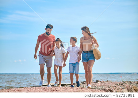A family walking on a shore holding hands 82725991