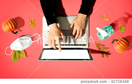 Person using a laptop computer with a mask and a sanitizer bottle Person using a laptop computer with a mask and a sanitizer bottle 82726388