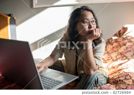 Young distracted female sitting in front of laptop 82726984