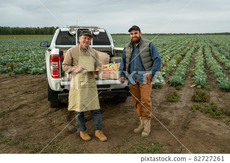 Two happy farmers in workwear standing by car trunk Two happy farmers in workwear standing by car trunk 82727261
