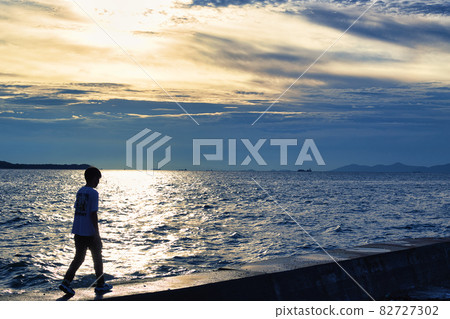 Boy taking a walk at the beach Boy taking a walk at the beach 82727302