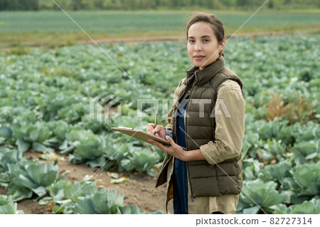 Young confident female farmer making notes in document 82727314