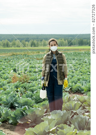 Young woman in protective workwear standing in cabbage field Young woman in protective workwear standing in cabbage field 82727326