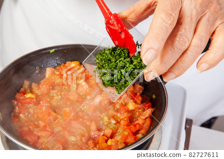 Preparation of the traditional Colombian hogao or criollo sauce (salsa criolla) made of onion, tomato, peppers and cilantro 82727611
