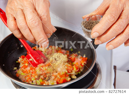 Preparation of the traditional Colombian hogao or criollo sauce (salsa criolla) made of onion, tomato, peppers and cilantro 82727614