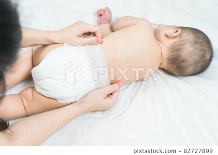Mother's hand taking care of little boy. Mom giving baby a diaper change on bed. Mother's hand taking care of little boy. Mom giving baby a diaper change on bed. 82727899