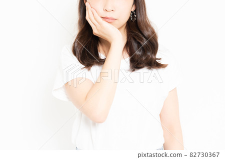 一位年輕女子穿著 T 卹，蛀牙疼痛，手放在臉頰上 82730367