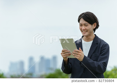 Young man operating a tablet PC Young man operating a tablet PC 82730804