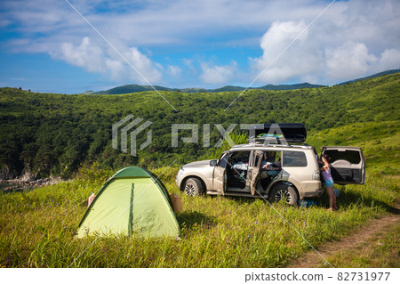 Woman taking off tourist equipment the car trunk 82731977