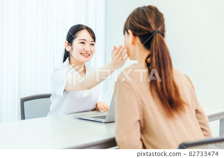 A woman in a white coat checking her face A woman in a white coat checking her face 82733474