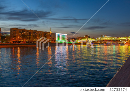 View of the colorful Bogdan Khmelnitsky bridge illuminated at night reflecting in the Moskova river. Moscow Kiyevsky railway station at night. Moscow, Russia View of the colorful Bogdan Khmelnitsky bridge illuminated at night reflecting in the Moskova river. Moscow Kiyevsky railway station at night. Moscow, Russia 82733574