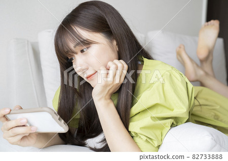 A woman watching a video on a smartphone 82733888