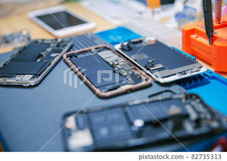 Phone repair concept several electronic devices taken apart into the components like the covers, circuit boards, bodies 82735313