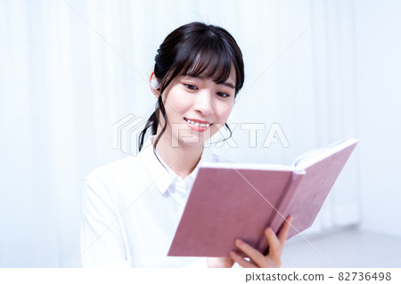 A young woman living alone who reads while listening to music in the living room on holidays A young woman living alone who reads while listening to music in the living room on holidays 82736498