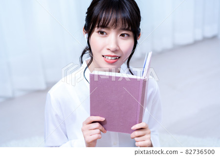 一個獨自生活的年輕女子,假期在客廳裡邊聽音樂邊讀書 一個獨自生活的年輕女子,假期在客廳裡邊聽音樂邊讀書 82736500