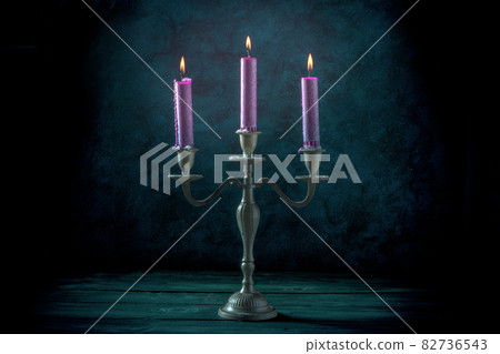 Candle magic. Purple candles in a vintage candle holder Candle magic. Purple candles in a vintage candle holder 82736543