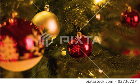 Red ball on a Christmas tree with a garland on the background of a wooden wall 82736727