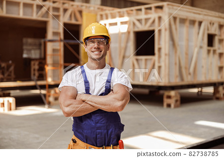 Cheerful young man builder standing at construction site 82738785