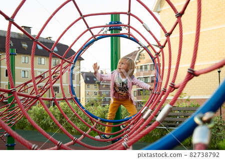 The little girl climbs ropes at the playground The little girl climbs ropes at the playground 82738792