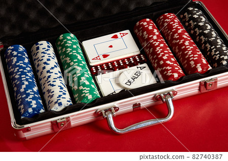 Poker set in metal suitcase. Risky entertainment of gambling. Top view on red background Poker set in metal suitcase. Risky entertainment of gambling. Top view on red background 82740387