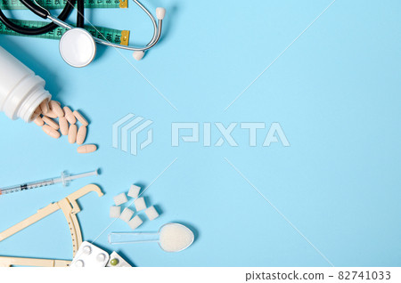 Scattered pharmaceutical pills, blisters of tablets, insulin syringe, stethoscope, caliper, measuring tape and refined sugar on blue background, copy space for Diabetes Awareness Day, 14 November Scattered pharmaceutical pills, blisters of tablets, insulin syringe, stethoscope, caliper, measuring tape and refined sugar on blue background, copy space for Diabetes Awareness Day, 14 November 82741033