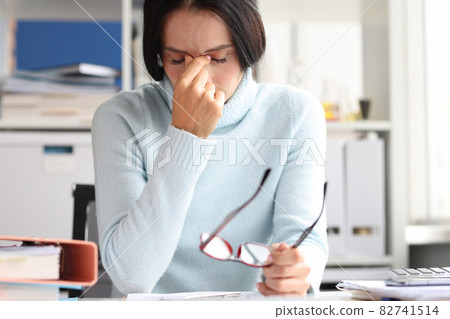 Painful depressed woman sits with eyes closed at workplace Painful depressed woman sits with eyes closed at workplace 82741514