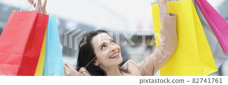 Young woman in suit picking up many colorful paper bags with purchases Young woman in suit picking up many colorful paper bags with purchases 82741761