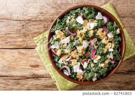 Gluten-free salad made with quinoa, onions, collard greens, feta and almonds dressed with vegetable oil close-up in a bowl. horizontal top view 82741803