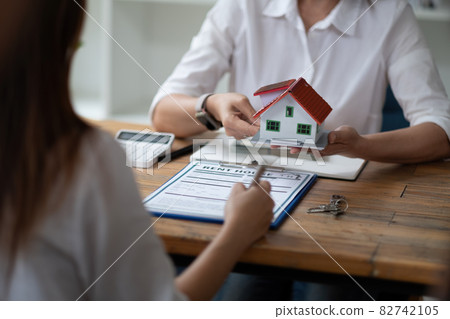 Estate agent give house model to customer after finished contract after about home insurance and investment loan Estate agent give house model to customer after finished contract after about home insurance and investment loan 82742105