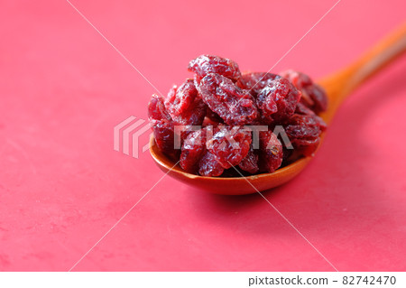 dried cranberries on a wooden spoon on red background dried cranberries on a wooden spoon on red background 82742470
