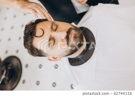 Close-up portrait of handsome bearded man at the barbershop, indoor. Beauty, selfcare, style, fashion, healthcare and male cosmetics concept. Close-up portrait of handsome bearded man at the barbershop, indoor. Beauty, selfcare, style, fashion, healthcare and male cosmetics concept. 82744138