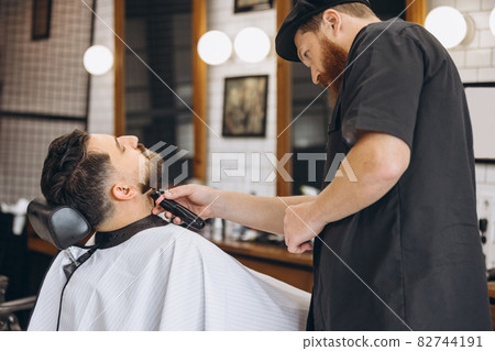 Professional barber, clipper cutting, shaving beard of regular customer at barbershop. Beauty, selfcare, style, fashion and male cosmetics concept. Professional barber, clipper cutting, shaving beard of regular customer at barbershop. Beauty, selfcare, style, fashion and male cosmetics concept. 82744191