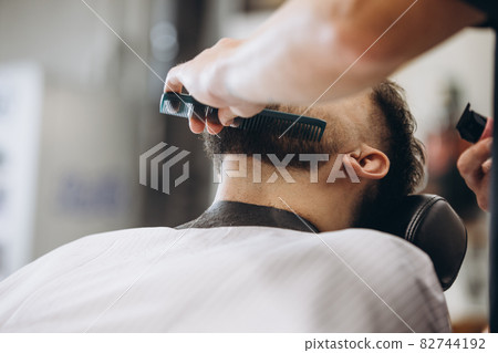 Professional barber, clipper cutting, shaving beard of regular customer at barbershop. Beauty, selfcare, style, fashion and male cosmetics concept. Professional barber, clipper cutting, shaving beard of regular customer at barbershop. Beauty, selfcare, style, fashion and male cosmetics concept. 82744192